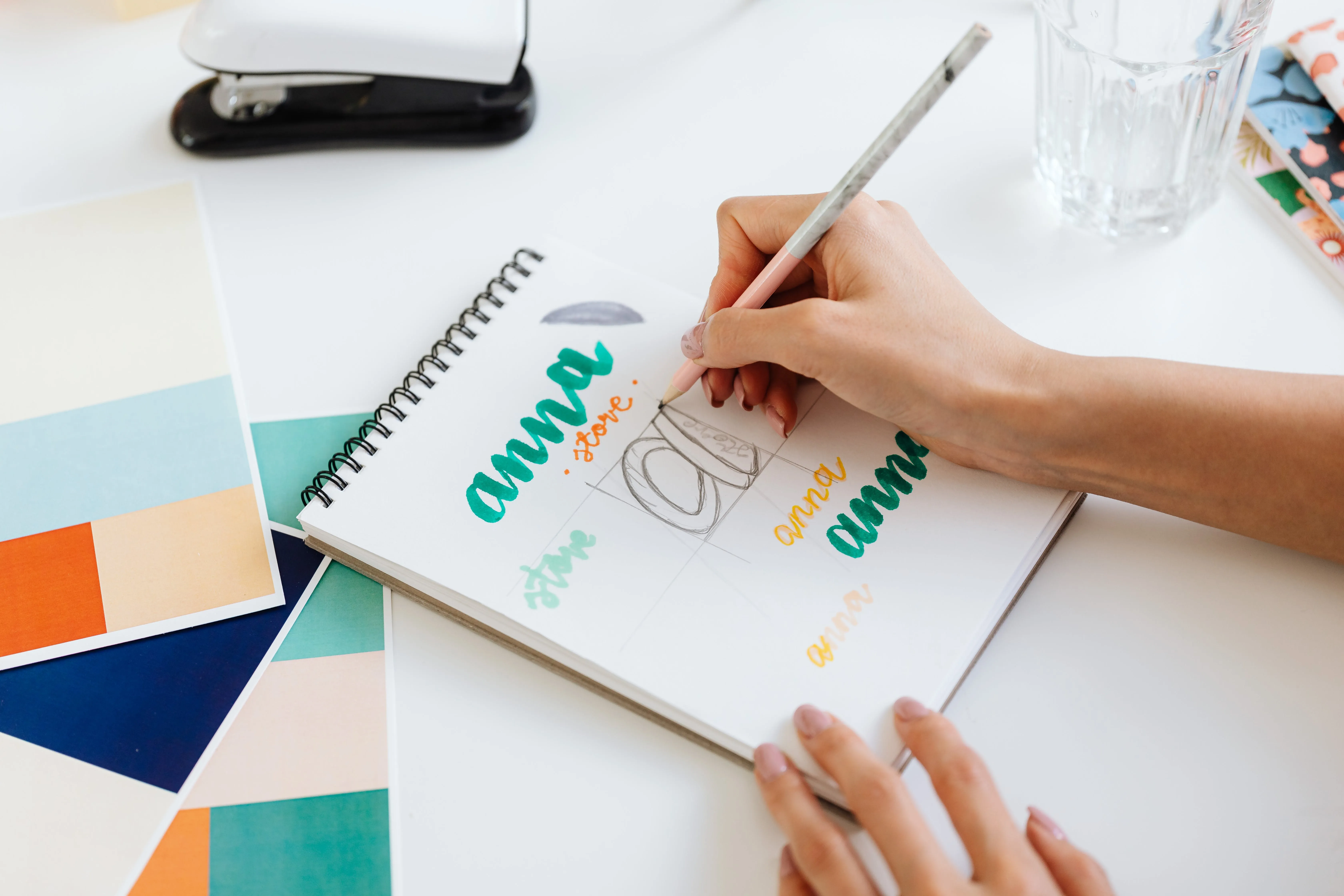 A picture of a hand drawing pictures on a notepad of a collection of graphic ideas.